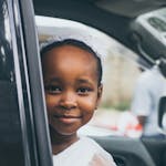 Adorable child smiling from vehicle in Dar es Salaam, Tanzania.