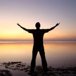 A person joyfully embracing the sunrise over a calm ocean, symbolizing freedom and solitude.