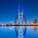Stunning night view of Bahrain World Trade Center with clear water reflections and modern skyline.