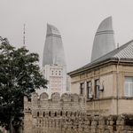 People walking by the ancient city walls with the iconic Flame Towers in the background, Baku, Azerbaijan.