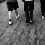 Black and white image capturing three people walking with motion blur effect.